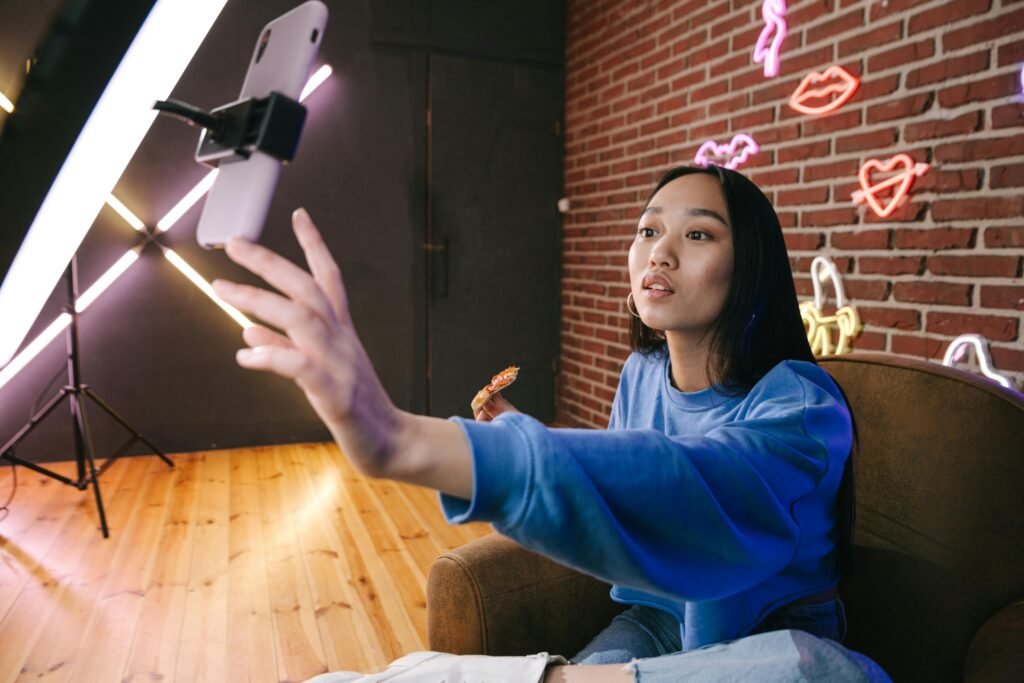 pexels-photo-7676406-7676406 Asian woman creates live stream content in stylish neon lit room.