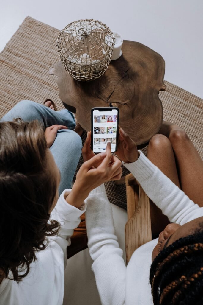 pexels-photo-5081918-5081918 Two people looking at social media on a smartphone at a wooden table.